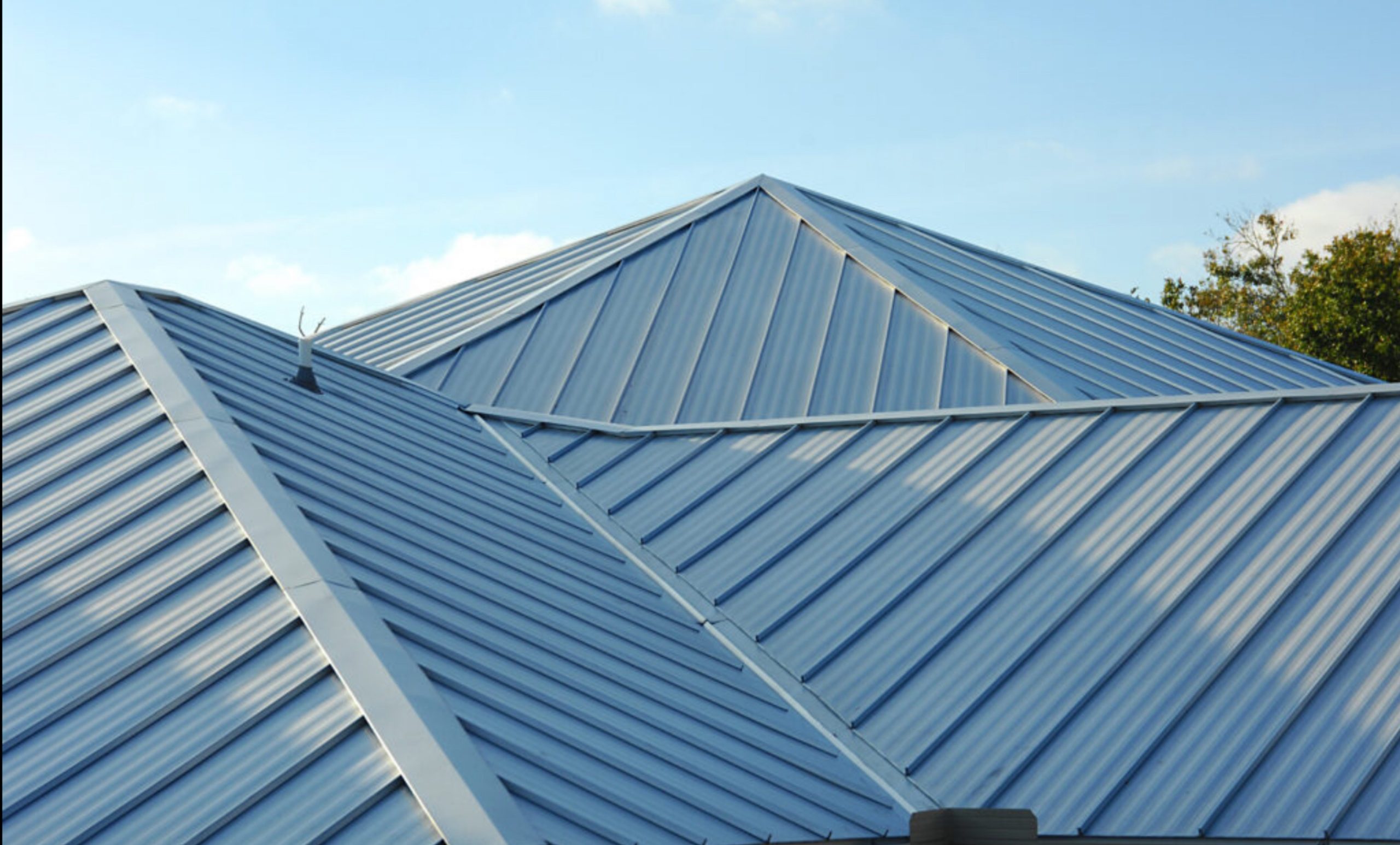 Roofer fastening a charcoal standing seam metal panel over exposed decking